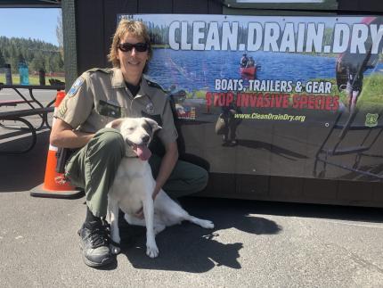Sgt. Pam Taylor sits next to mussel-sniffing dog (Puddles) in front of clean, drain, dry sign
